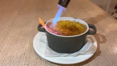 Şef creme brulee 'yi gaz ocağıyla pişirir, evde tatlı pişirir, evde yemek pişirir, profesyonel yemek blogu yazarları olur. Yüksek kalite 4k görüntü