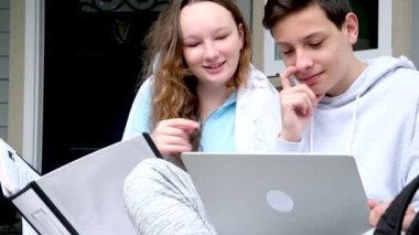 Ergen, evden birlikte online eğitim almak için dizüstü bilgisayar ve tablet kullanıyor. Karantina konsepti verandada oturup kulağına fısıldıyor. Ev ödevlerini yaparken büyük beyaz klasörde eğlenmene bak.