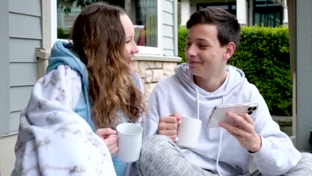 Genç Kız Verandada Oturmuş Sıcak Çay Içiyor Akıllı Telefonuna Bakıyor — Stok video