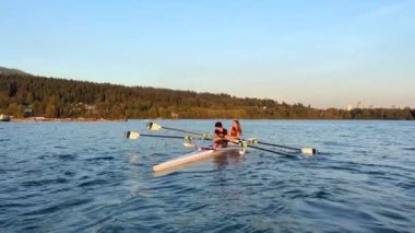 Bir teknede kuru kürekler iki genç denizin ortasında bir dağın arka planında bir kız ve bir oğlan bir gölün ortasında 2022 sonbaharında Kanada Vancouver 'da