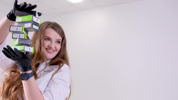 Blt Straumann 一位戴乳胶黑色手套的漂亮女医生 手持6盒假牙植入物 并在白色工作室背景空间治疗假牙 用于文字广告 — 图库视频影像