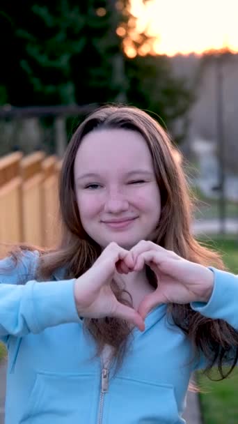 Beyaz Elbiseli Gülümseyen Genç Bir Kadın Kameraya Bakıyor Elleriyle Kalp — Stok video