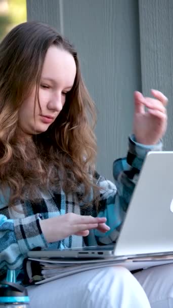 10代の女の子は14歳で仕事を探すためにラップトップのオンライントレーニングを開きます友人との通信若い女性の深刻な顔と異なるプログラムでアウトライン作業を準備します — ストック動画