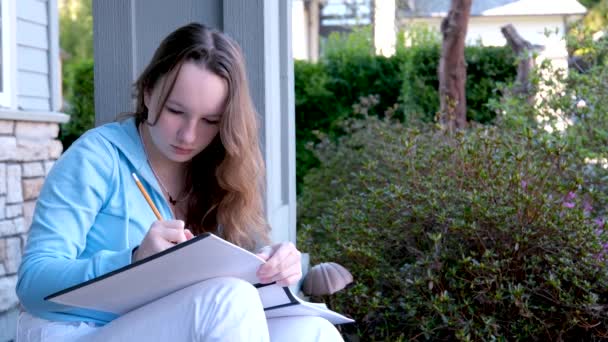 소녀는 흰색큰 스케치북을 현관에 앉아서 온라인 문제를 합니다 — 비디오