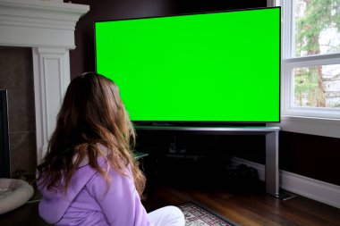 Dolly 'nin Yeşil Ekran Çekimi' ni izliyorum. At kuyruklu kız evde büyük ekran televizyon seyrediyor. Yeşil ekran görüntüsü. TV ekranına nokta Yüksek kalite