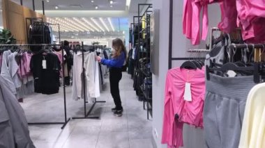 Genç kız kıyafet alışverişi yapıyor ve moda kadını için yeni kıyafet seçiyor. Alışveriş yaparken iyi görünmek istiyor. Gençlik alışveriş sinirleri.