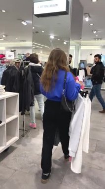 Genç kız kıyafet alışverişi yapıyor ve moda kadını için yeni kıyafet seçiyor. Alışveriş yaparken iyi görünmek istiyor. Gençlik alışveriş sinirleri.