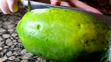 Kadın elleri papayayı ikiye böler. Keskin bıçağı dikkatlice dilimle. Yüksek kalite 4k görüntü