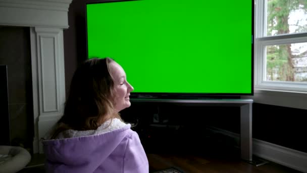 テレビ緑の画面ドリーショットを見て 自宅で大きな画面テレビを見てポニーテールの女の子 ドリー撮影 緑の画面の映像 テレビ画面のポイント高品質 — ストック動画