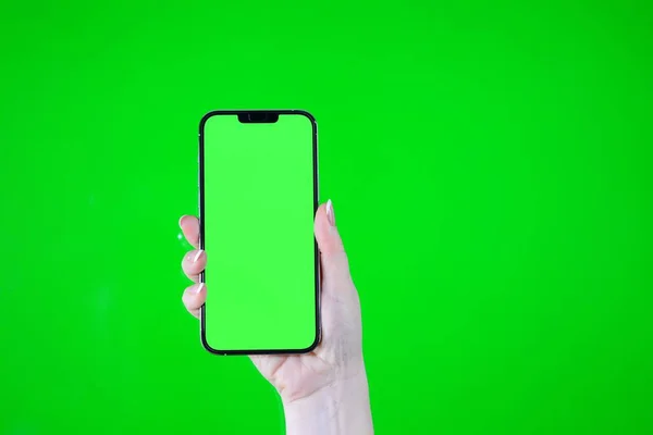 Child hand touching clicking on mobile phone with chromakey screen. Little Baby Finger Taps in center of blank phone green display. Close up. Using smartphone device. Top view Flat lay.