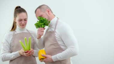 Mutlu çift ilk buluşmada mutfakta birlikte lezzetli bir yemek hazırlıyor, eşler sohbet ediyor sıcak sohbetin ve yemek pişirmenin tadını çıkarıyor, adam elinde kereviz tutan maydanozlu kadını kokluyor.