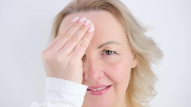 Kadın yüz temizleme yüz portresinden makyajı kaldırıyor. Kız kameraya bakarak yüz derisini siliyor. Cilt bakımı ve temizlik prosedürü. Losyonla cilt nemlendirici