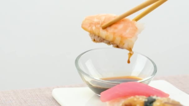 白を背景に箸で食べることを学ぶ初心者が箸で醤油で寿司を浸す方法を学ぶ失敗した試みの作品 — ストック動画