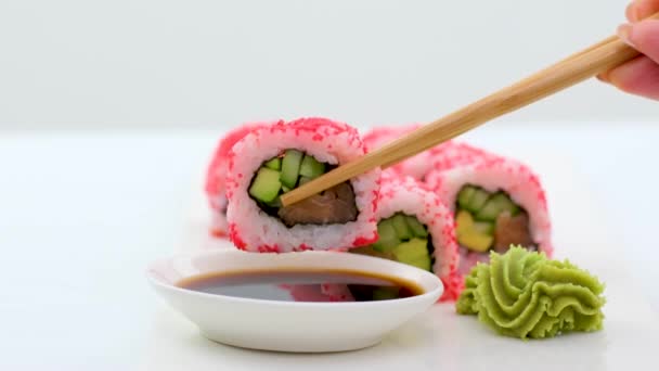 Sticks把Sushi从Sushi盒子里带走 种类繁多的寿司与红色鱼子酱 费城奶酪和筷子特写 一套美味的日本寿司滚在一块黑色的石板上 — 图库视频影像