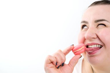 Beyaz arka planda kurabiye yiyen mutlu ve tatmin olmuş bir kadın. Tatlı reklamları, keyifli hayatlar. Gülümseme, aşırı kilolu mankenler.