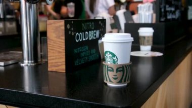 Vancouver 'da Kanada' da Starbucks beyaz önlüklü ve maskeli kadınların arkasında çeşitli içeceklerden oluşan kahve hazırlıyor.