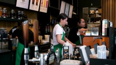 Vancouver 'da Kanada' da Starbucks beyaz önlüklü ve maskeli kadınların arkasında çeşitli içeceklerden oluşan kahve hazırlıyor.