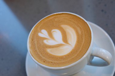 Beyaz kapuçino kahve fincanında ağaç desenli bir fincan kahve, latte sanatıyla izole edilmiş. Yüksek kalite fotoğraf