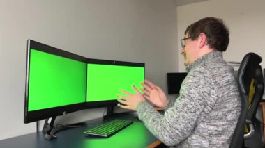 Yazan adam yeşil ekran ofisi. Ofisinde çalışan çift yeşil ekran monitörlü bir adam.