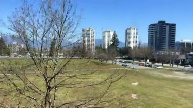 Vancouver, Surrey 'de hareket halindeki trenin penceresinden görünen çıplak ağaç istasyonları gökdelenler teknoloji merkezleri Kanada 2023 yılının farklı video trafiğinin büyük blokları.