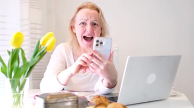 Bir kadın mesaj yazıyor ya da bir site açıyor gibi görünüyor. Sonra ekranı parmakla gülmek yerine yeşile boyuyor. Gülümseme, mesaj ve reklam için parmağını beyazlar içinde dizüstü bilgisayarın yanına koyuyor.