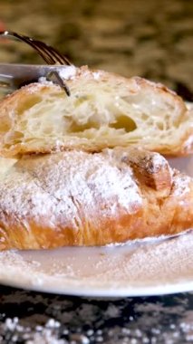 Yakın plan lezzetli iştah açıcı taze kruvasan üzerine pudra şekeri serpiştirilmiş mermer masa beyaz tabağı lezzetli öğle yemeği atıştırmalığı gözenekli yapı gözenekli diyet yeri reklam menüsü Fransız kahvaltısı