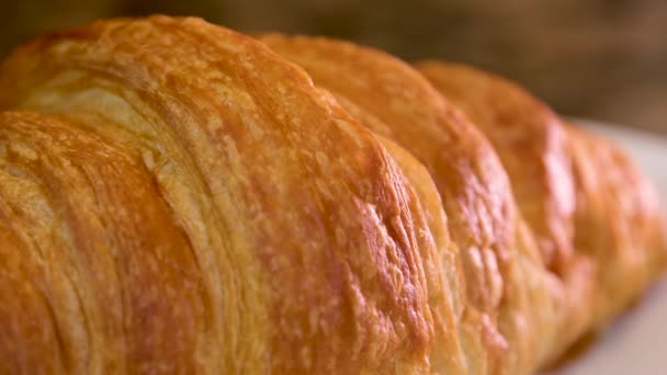 閉じるおいしい食欲をそそる新鮮なカリカリのクロワッサン大理石のテーブルの上に粉砂糖を振りかけた白いプレートおいしい食べ物ランチスナック多孔質構造ベーキングダイエット場所広告メニューフランスの朝食 — ストック動画