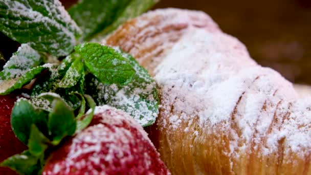 美味的新鲜烤羊角面包放在盘子里 戴着手套 把它分解成不同的小块 法国早餐午餐的结构是多孔的 可以看到吃带有草莓和薄荷糖的羊角面包 — 图库视频影像