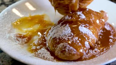 Karamel şurubu ile doldurulmuş beyaz tabakta lezzetli kruvasan farklı yönlere yayılmış şeker tozlu lezzetli iştah açıcı çay için çok tatlı Fransız tatlısı öğle yemeği servisi.