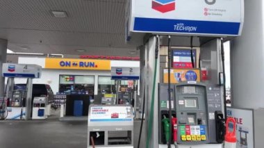 Chevron. Arabanın yakıt ikmali yapılan benzin istasyonu. Benzin doldurma işlemi. Benzin makinası insanları.