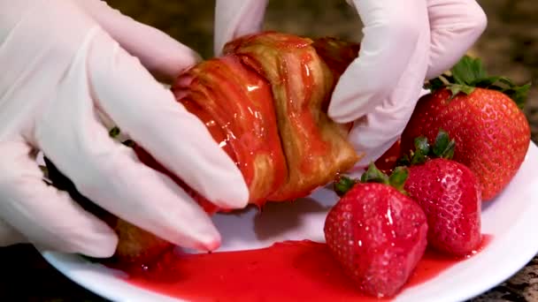 Handschuhte Hände Brechen Köstliche Frische Croissant Durchtränkt Mit Rotem Sirup — Stockvideo