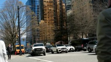 Burrard İstasyonu 'ndaki ofis binaları çalışanları tramvay trafik ışıklarına doğru koşuşturuyor. Erkekler ve kadınlar caddeyi geçerek toplu taşıma şehrine giderler. Kanada Vancouver 12.04.2023