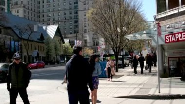 Burrard İstasyonu 'ndaki ofis binaları çalışanları tramvay trafik ışıklarına doğru koşuşturuyor. Erkekler ve kadınlar caddeyi geçerek toplu taşıma şehrine giderler. Kanada Vancouver 12.04.2023