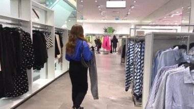 Genç kız kıyafet alışverişi yapıyor ve moda kadını için yeni kıyafet seçiyor. Alışveriş yaparken iyi görünmek istiyor. Gençlik alışveriş sinirleri.
