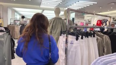 Genç kız kıyafet alışverişi yapıyor ve moda kadını için yeni kıyafet seçiyor. Alışveriş yaparken iyi görünmek istiyor. Gençlik alışveriş sinirleri.