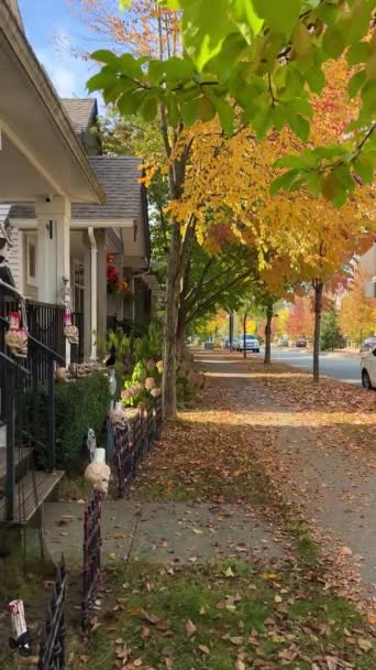 休日の前に飾られた秋のハロウィーンの家カメラはゆっくりとすべての瞬間を示していますポーチに立つピエロスケルトンと秋の黄色の葉カナダバンクーバー — ストック動画