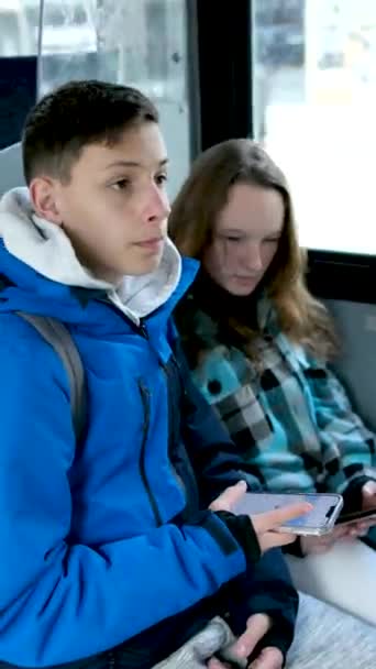 两个身穿蓝色衣服的年轻人坐在一辆加拿大温哥华的公共汽车上 秋天的冬天 他们穿着一套冬季的运动服 用手机搜索地球定位游客的真实生活 — 图库视频影像