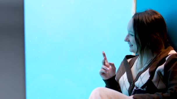 十代の女の子はシールが海のライオンを泳ぐ水族館のガラスのそばに座っています彼女は幸せな笑顔です人の子供の喜びビデオで撮影する指を見るバンクーバー水族館 Bc州 カナダ — ストック動画