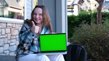 Yeşil ekranlı dizüstü bilgisayarı olan mutlu bir kız sokak delikanlısının üzerinde oturmuş internetteki reklam reklamını işaret ederek ilginç spor alışverişlerini öğreniyor.