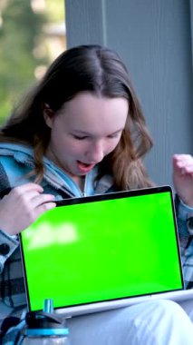 Yeşil ekranlı dizüstü bilgisayarı olan mutlu bir kız sokak delikanlısının üzerinde oturmuş internetteki reklam reklamını işaret ederek ilginç spor alışverişlerini öğreniyor.