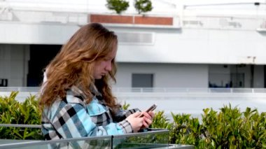 Genç turist kız Vancouver 'la Waterfront İstasyonu' nun şehir merkezinde beyaz yelkenli arka planında oynayın. Telefonlara bakar ve konum tespiti arar.