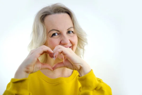 stock image portrait of a young woman doing a heart gesture. High quality photo