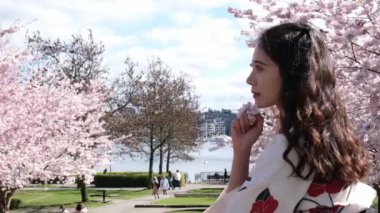 Kiraz çiçeğiyle gülümseyen çekici Japon kadın, Ağır çekim. Yüksek kalite 4k görüntü