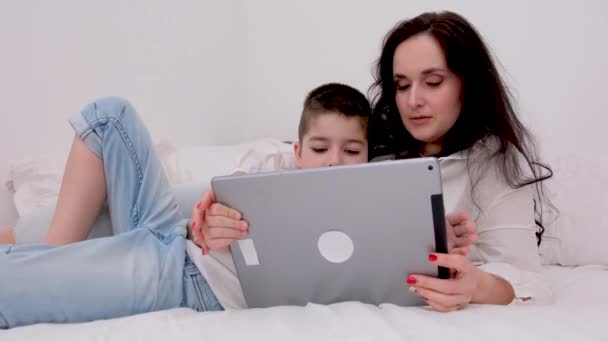 快乐的年轻妈妈教可爱的儿子在家里用智能手机学习有趣的应用程序 微笑的妈妈抱着学龄前的男孩玩着好玩的看手机放松 — 图库视频影像