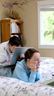 Çevrimiçi öğrenim gören gençler dizüstü bilgisayarın yanında oturup ödev yapıyor ve film arkadaşları seyrediyor sınıf arkadaşları yatak odasında birbirleri gibi gülümsüyor 