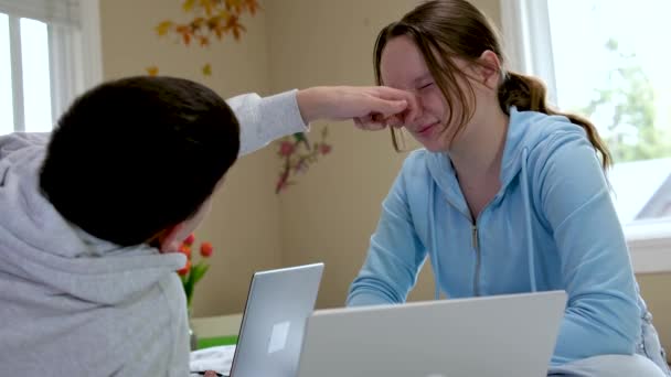 十代の若者たちは 周りの愚かを学びます男の子は鼻で女の子をつかむ部屋の友人でコンピュータの近くに手を引く楽しい時間を一緒に過ごす — ストック動画