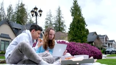 Çevrimiçi öğrenim, açık havada erkek çocukları piknik, pizza yemek, ev ödevi, dizüstü bilgisayarla iletişim sorunu, ciddi yüzleri çözme, sınıf arkadaşları.