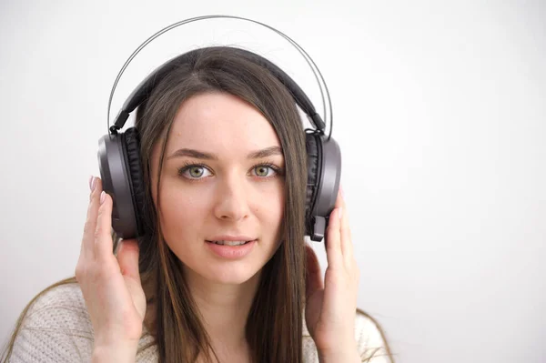 stock image Smiling girl relaxing at home, she is playing music using a smartphone and wearing white headphones. High quality photo