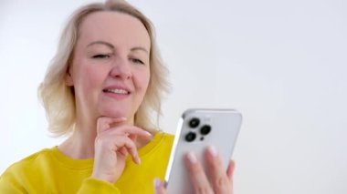 İyi haber, mutlu kadın dans eden, beyaz arka planda izole edilmiş bir telefon, neşeli bir gülümseme, heyecanlı bir kadının internetten para kazanması. Yüksek kalite 4k görüntü