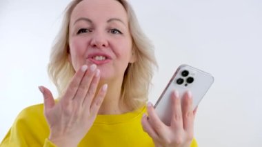 Milenyum sosyal medya blogcusu akıllı telefondan hava öpücüğü yolluyor ve el sallıyor. Blog ya da anılar için selfie çek. Pastel arka planda pembe saçlı yeni konsept stüdyo kadını.